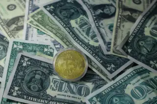 Ilustrasi: Koin emas Bitcoin di atas tumpukan uang kertas satu dolar Amerika Serikat.
