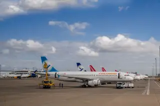 Ilustrasi: Beberapa pesawat komersial terparkir di apron bandara di bawah langit cerah berawan.