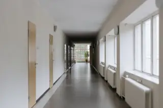 Ilustrasi: Lorong panjang sebuah gedung institusi yang kosong dengan deretan pintu dan jendela.