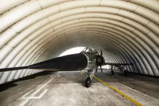 Ilustrasi: Sebuah pesawat jet tempur militer terparkir di dalam hanggar berbentuk lengkung.