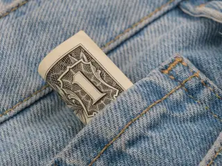 Ilustrasi: Gulungan uang satu dolar AS terselip di saku celana jeans biru.