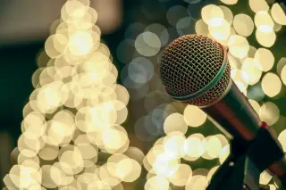 Ilustrasi: Mikrofon pada tiang dengan latar belakang pantulan cahaya bokeh yang hangat.
