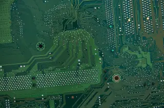 Ilustrasi: Tampilan jarak dekat jalur sirkuit elektronik dan titik solder pada papan sirkuit hijau.