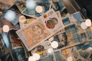 Ilustrasi: Tumpukan uang kertas pound sterling Inggris dan koin dengan pantulan cahaya.