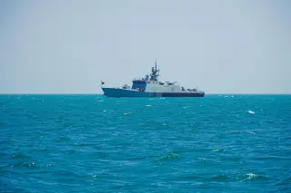 Ilustrasi: Sebuah kapal patroli militer berlayar di perairan laut biru yang luas di bawah langit cerah.