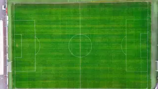 Ilustrasi: Pemandangan udara lapangan sepak bola hijau dengan garis putih bersih.