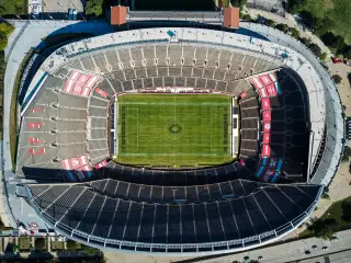 Ilustrasi: Pemandangan udara stadion sepak bola besar yang kosong dengan lapangan hijau.