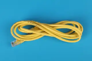 Ilustrasi: Gulungan kabel ethernet berwarna kuning di atas latar belakang biru.