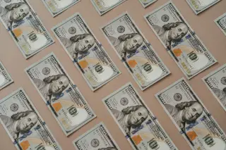 Ilustrasi: Deretan uang kertas seratus dolar AS tertata rapi di atas permukaan datar.