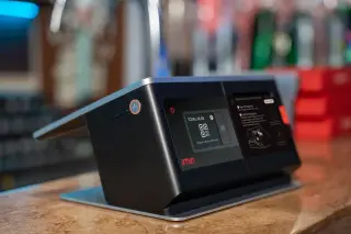 Ilustrasi: Perangkat mesin kasir digital layar sentuh dengan tampilan kode QR di atas meja konter.