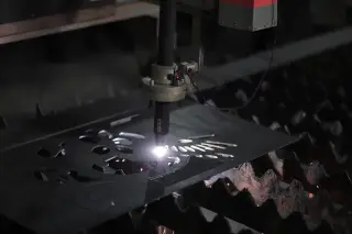 Ilustrasi: Mesin pemotong laser sedang memotong pelat logam dengan presisi di bengkel industri.