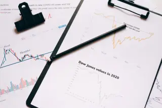 Ilustrasi: Kertas grafik pergerakan saham dan pensil di atas papan klip.