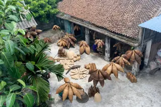 Ilustrasi: Pemandangan dari atas halaman rumah tradisional dengan jemuran aneka kerajinan anyaman bambu.