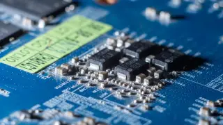 Ilustrasi: Foto makro komponen elektronik dan sirkuit terpadu pada papan sirkuit biru.