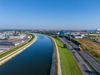 Ilustrasi: Pemandangan udara kanal air di samping jalan raya dan kompleks pergudangan.