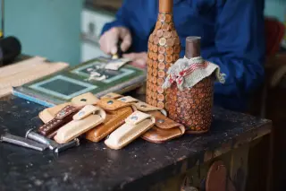 Ilustrasi: Produk kerajinan kulit buatan tangan tertata di atas meja kerja seorang perajin.