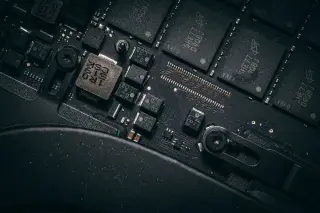 Ilustrasi: Foto makro komponen sirkuit elektronik dan mikrocip hitam dengan detail jalur sirkuit.