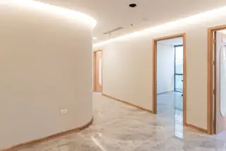 Ilustrasi: Lorong gedung modern yang bersih dan kosong dengan lantai marmer serta pintu kayu.