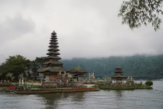 Ilustrasi: Pura Ulun Danu Beratan di tepi danau dengan latar perbukitan berkabut.