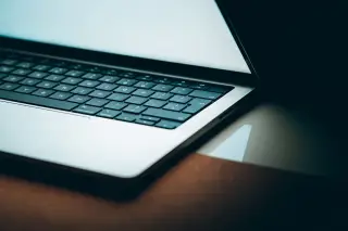 Ilustrasi: Tampilan jarak dekat keyboard dan layar laptop di atas meja.