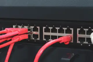 Ilustrasi: Kabel jaringan merah terpasang pada porta perangkat switch atau server.