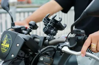 Ilustrasi: Stang sepeda motor dengan dudukan ponsel yang dipegang pengendara.