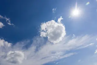 Ilustrasi: Langit biru cerah dengan awan putih dan pancaran sinar matahari terik.