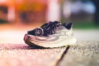 Ilustrasi: Sepasang sepatu lari dan jam tangan pintar diletakkan di atas permukaan jalan.