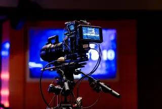 Ilustrasi: Kamera video profesional terpasang pada tripod di dalam sebuah studio rekaman.