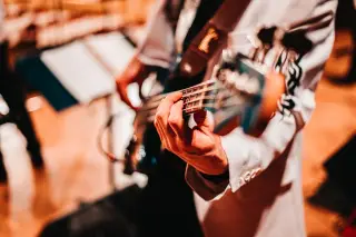 Ilustrasi: Tangan seorang musisi yang sedang memainkan gitar bas di atas panggung.