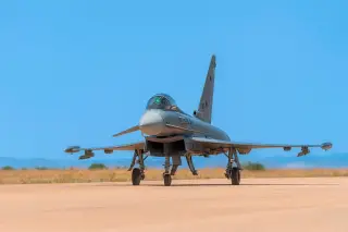 Ilustrasi: Sebuah jet tempur militer terparkir di landasan pacu dengan latar belakang langit biru.