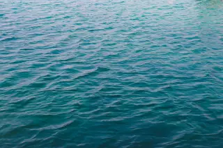 Ilustrasi: Permukaan air laut biru dengan riak gelombang tenang.