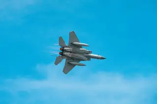 Ilustrasi: Sebuah jet tempur militer terbang di langit biru cerah.