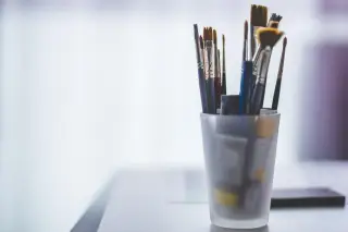 Ilustrasi: Sejumlah kuas lukis diletakkan di dalam gelas kaca buram di atas meja.