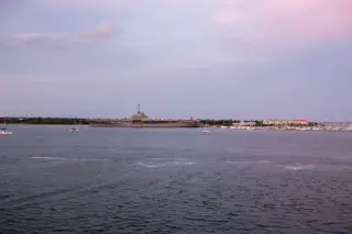 Ilustrasi: Kapal induk militer berlabuh di perairan dekat pelabuhan dengan langit senja.