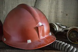 Ilustrasi: Helm keselamatan kerja berwarna merah tergeletak bersama masker respirator.