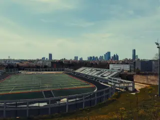 Ilustrasi: Stadion sepak bola dengan latar belakang deretan gedung pencakar langit kota.