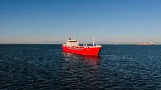 Ilustrasi: Kapal tanker merah berlayar di perairan laut luas di bawah langit cerah.