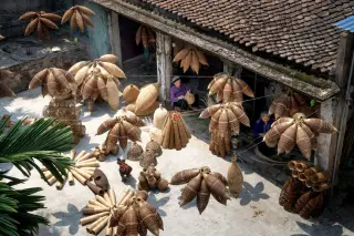 Ilustrasi: Warga menganyam dan menjemur kerajinan bambu di halaman rumah tradisional.