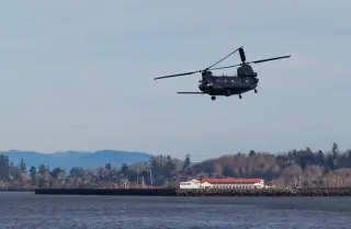 Ilustrasi: Sebuah helikopter militer terbang rendah di atas perairan dengan latar belakang daratan.