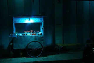 Ilustrasi: Gerobak kayu bertuliskan Wedang Ronde diterangi lampu di pinggir jalan pada malam hari.