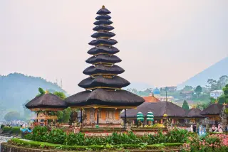 Ilustrasi: Pura bertingkat khas Bali di tepi danau dengan taman bunga di sekelilingnya.