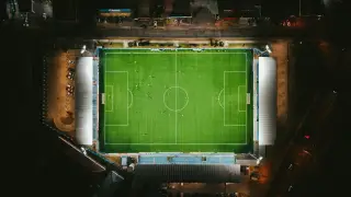 Ilustrasi: Pemandangan udara stadion sepak bola dengan lampu menyala di malam hari.