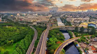 Ilustrasi: Pemandangan udara jalan layang dan kawasan perkotaan di bawah langit senja berawan.
