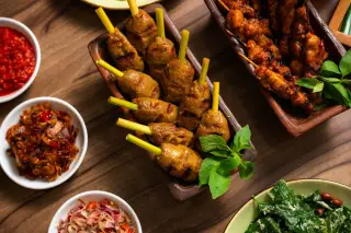 Ilustrasi: Sajian sate lilit, sate ayam, dan aneka sambal tradisional di atas meja kayu.