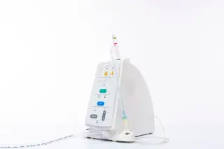 Ilustrasi: Sebuah perangkat medis putih dengan selang dan tombol kontrol berlatar belakang putih polos.