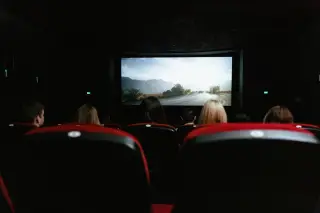 Ilustrasi: Penonton duduk di kursi bioskop menyaksikan tayangan film di layar lebar.