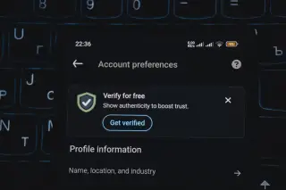 Ilustrasi: Layar ponsel menampilkan menu verifikasi akun di atas papan ketik laptop.