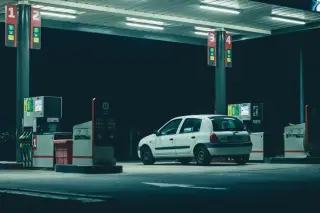 Ilustrasi: Sebuah mobil putih terparkir di stasiun pengisian bahan bakar pada malam hari.