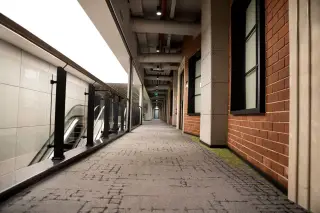 Ilustrasi: Lorong gedung modern yang sepi dengan karpet bermotif dan dinding bata ekspos.